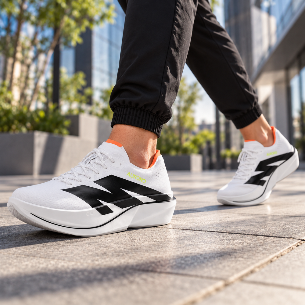 Person walking in white AURORO shoes on a city sidewalk